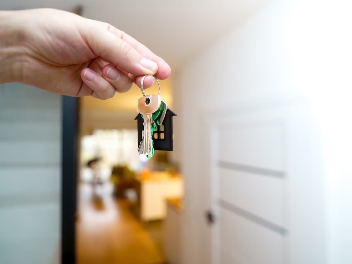 A hand holding keys in front of an open apartment door